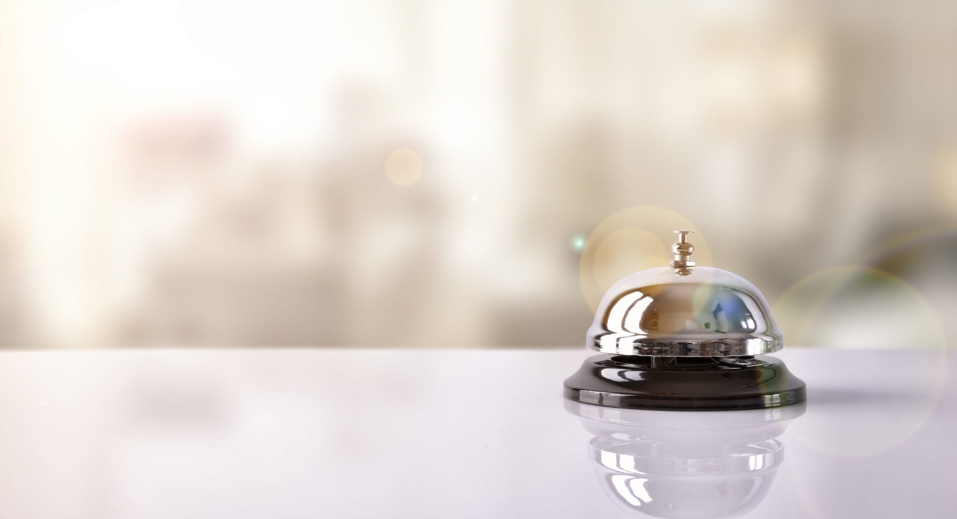 Hotel service bell on a table white glass and simulation hotel background. Concept hotel, travel, room